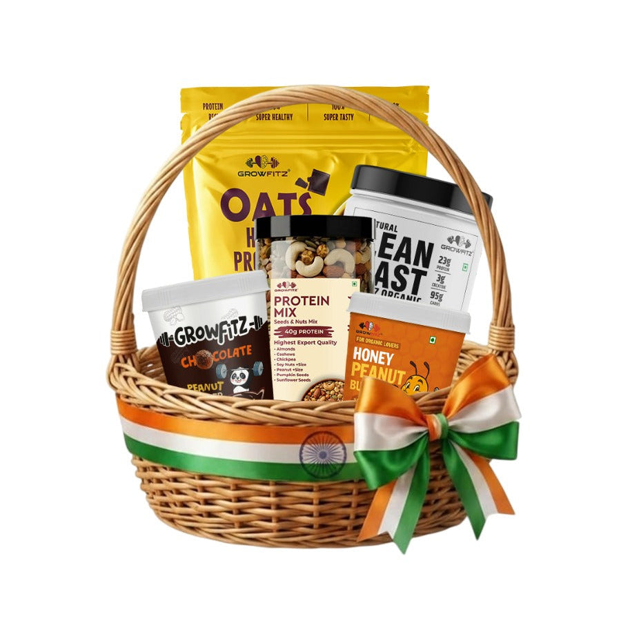 A wicker gift basket with a green, white, and orange ribbon, filled with various snack and protein products including Oats Meal, Beanast Protein Powder, and Honey Peanut Butter, on a white background.