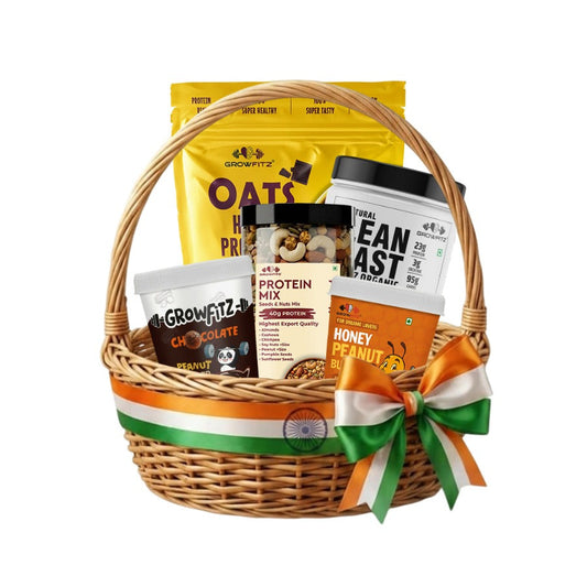 A wicker gift basket with a green, white, and orange ribbon, filled with various snack and protein products including Oats Meal, Beanast Protein Powder, and Honey Peanut Butter, on a white background.